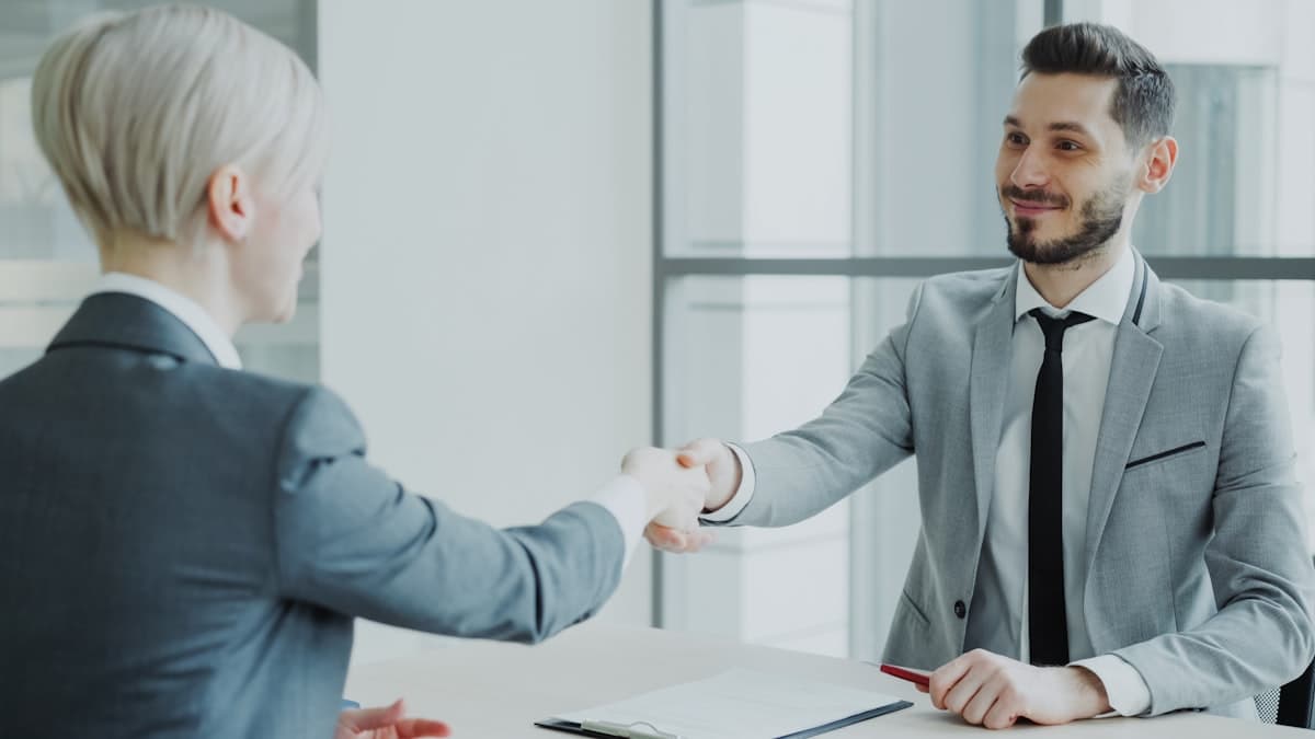 Business handshake across a table, representing recovery follow-up and borrower interaction